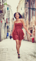 Happy beautiful woman in red summer dress walking and running joyful and cheerful smiling in...