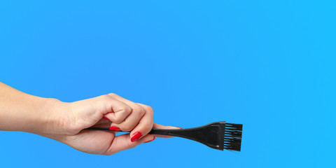 Woman hand with a hair dresser's tools and accessories isolated on color background