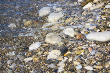 sea pebble beach with multicoloured stones, waves with foam