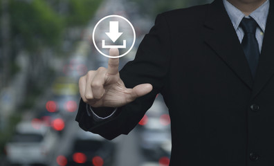 Businessman pressing download icon over blur of rush hour with cars and road, Business internet concept