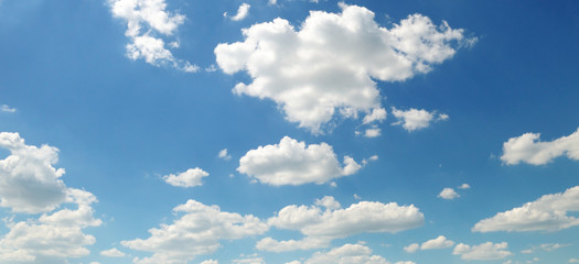 Light cumulus clouds against the blue sky. Wide photo.