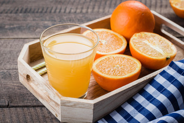 Fresh Orange Juice in Glass in Wooden Tray on old wooden table background. Citrus Drink Lemonade. Copy space