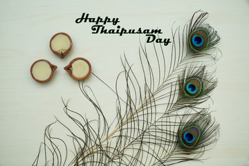 Top or flat lay view of a peacock feathers on a wooden background with a words HAPPY THAIPUSAM DAY....