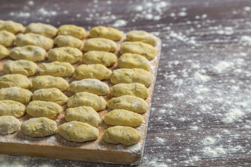 Uncooked gnocchi in flour on a cutting Board, cooked at home