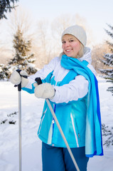 beautiful blond girl with ski poles in hands during a short rest with a smile looks directly at the camera