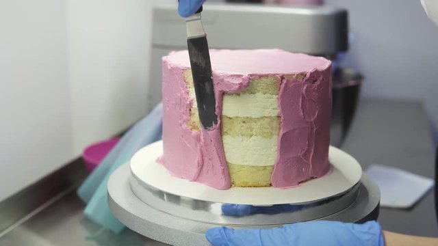 The process of decorating a cake with purple cream cover. Confectioner equates biscuit cream using pastry spatula