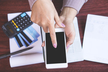 woman hand holding smart phone calculating her monthly expenses with credit card,saving account...