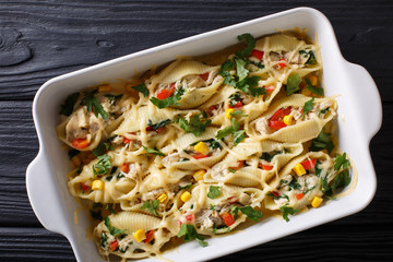 Casserole from conchiglioni pasta stuffed with chicken, mushrooms and vegetables close-up on a table. horizontal top view