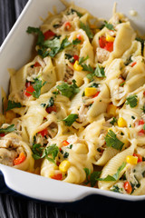 Baked conchiglioni pasta stuffed with chicken, mushrooms and vegetables close-up in a baking dish. vertical