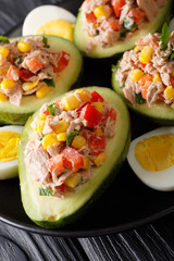 Fresh avocado stuffed with a salad of tuna and vegetables close-up on a plate. vertical