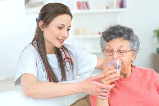 Doctor making sure senior woman takes her medication