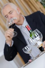 man sniffing red wine in glass