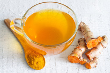 Raw roots of tumeric and tea on white planks detox concept