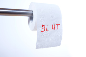 Das Wort Blut in roten Lettern auf einer Toilettenpapier-Rolle