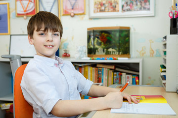 Portrait of Adorable boy holding pencil and sitting in the children room, Kid sitting in the room...