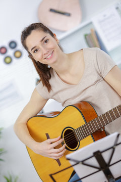 beautiful girl teenager in shirt and torn jeans playing guitar