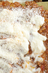 Fototapeta premium How to cook Italian lasagna,vertical background with close up on a raw italian lasagna, from above. ready to be baked, with ragu, bechamel grated cheese.