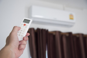 A man use remote controller to set air conditioner temperature in the room.Hand holdind control remote switch of home air conditioner