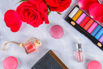Obraz na płótnie Canvas Roses, eye shadow, purse, perfume, macaroons on a gray table. Flat lay. Top view. Women's things. Copy space.