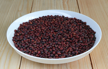 Red bean on white plate with wood plate background.