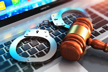 Handcuffs and judge mallet on laptop keyboard