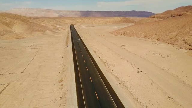 Still aerial of a silver SUV traveling through the desert in Peru