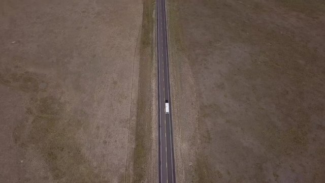 Drone aerial of Camper Car driving down empty road from above in empty wilderness landscape