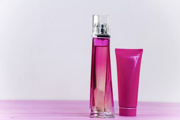 perfume bottle and cream on a pink wooden background