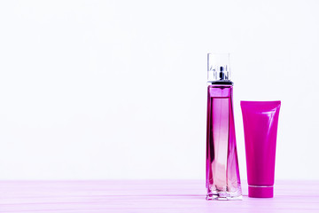 perfume bottle and cream on a pink wooden background