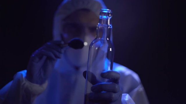 Criminalist lifting fingerprints from bottle at crime scene, search for evidence