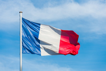 French flag waggling in the wind with sky in background