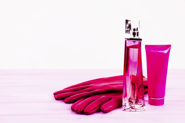 perfume bottle and cream on a pink wooden background