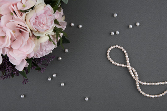 bouquet of roses with pearl necklace on grey background