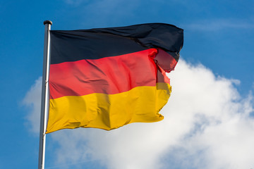 German flag waggling in the wind with blue sky