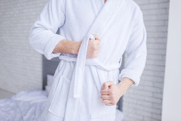 mid section of man wearing bathrobe at home