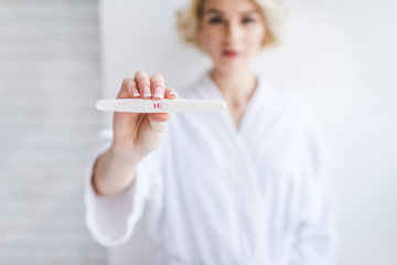 close-up view of young woman holding positive pregnancy test