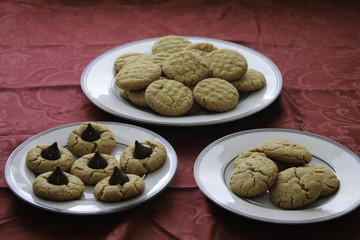 Homemade peanut butter cookies. Three different types of cookies on white plates. Table with red tablecloth