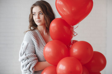 Valentine Beauty girl with colorful air balloons laughing, isolated on background. Beautiful Happy Young woman. holiday party. Joyful model having fun, playing and celebrating with red color balloon