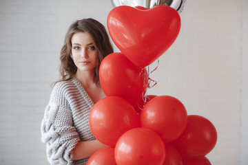 Valentine Beauty girl with colorful air balloons laughing, isolated on background. Beautiful Happy Young woman. holiday party. Joyful model having fun, playing and celebrating with red color balloon