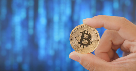 Hand holding bitcoin over digital abstract background
