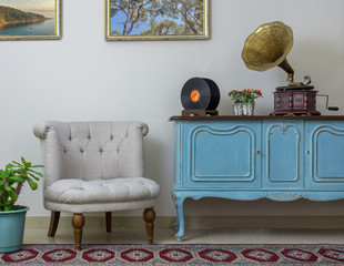 Vintage interior of retro off white armchair, vintage wooden light blue sideboard, old phonograph...