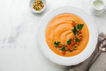 Homemade pumpkin soup in white ceramic dish on an old concrete or stone background. Selective focus.  Top view. Copy space.