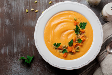 Homemade pumpkin soup in white ceramic dish on an old concrete or stone background. Selective focus.  Top view. Copy space.