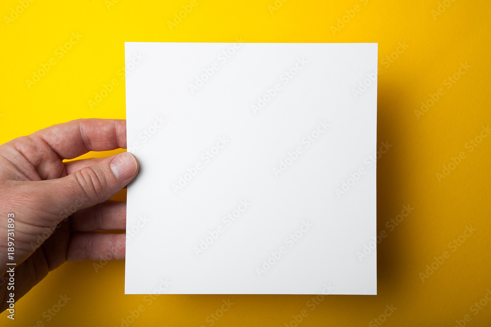 Poster empty square layout in hand on a yellow background.