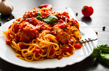 pasta spaghetti with meatballs in tomato sauce on a plate on dark wooden background