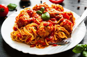 pasta spaghetti with meatballs in tomato sauce on a plate on dark wooden background