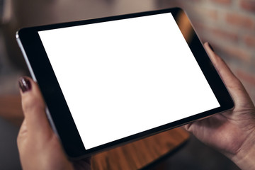 Mockup image of a woman holding black tablet pc with blank white desktop screen in cafe