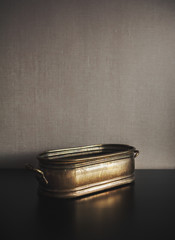 Vintage brazen metal bowl on dark background