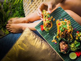 Woman holding plate with healthy vegan jackfruit tacos