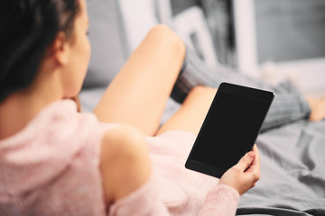 Girl sitting on bed in the morning and using tablet for reading news
